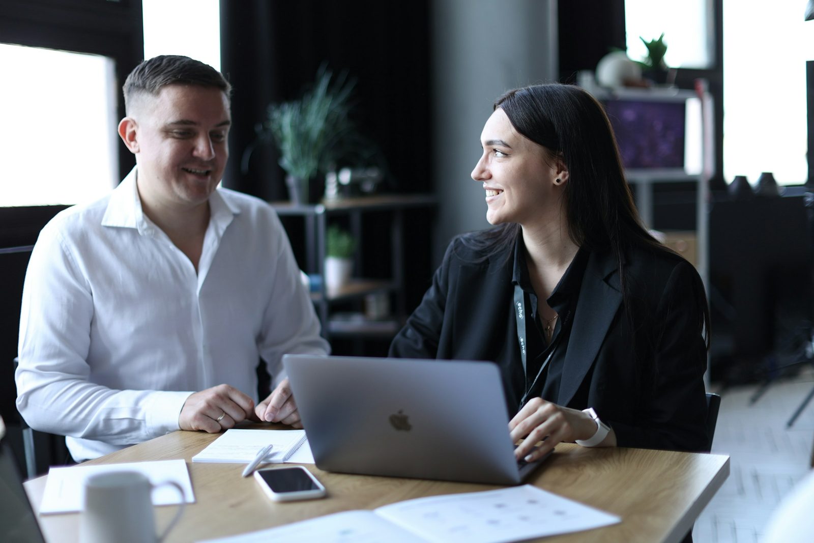 Colegas de trabalho conversando e sorrindo numa mesa do escritório